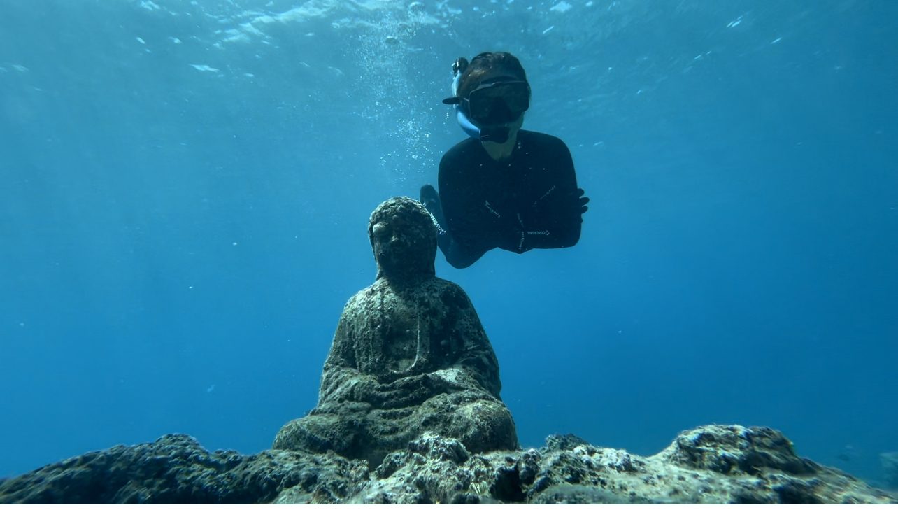 Diver exploring underwater Buddha statue