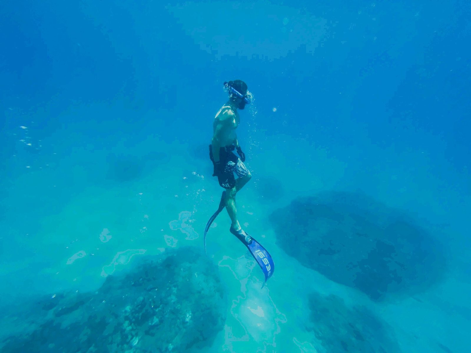 Freediver ascending through turquoise water