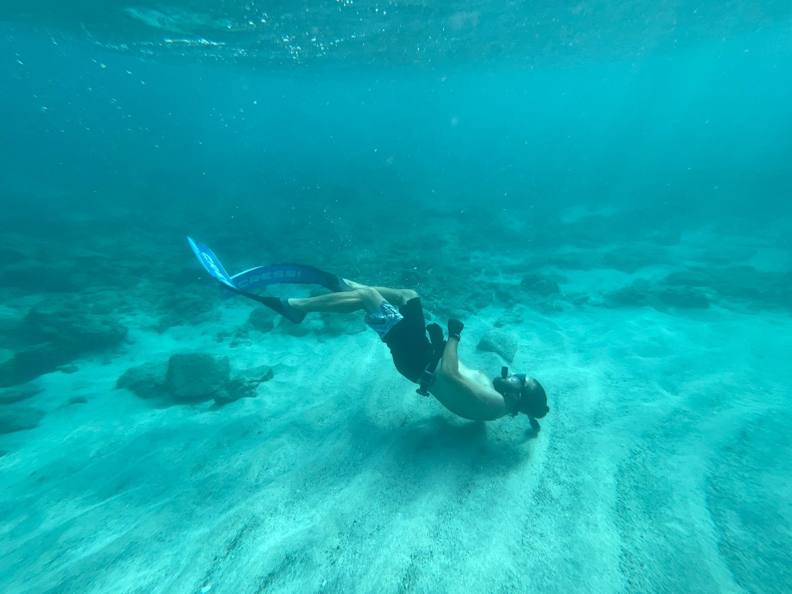 Freediver descending near sandy bottom